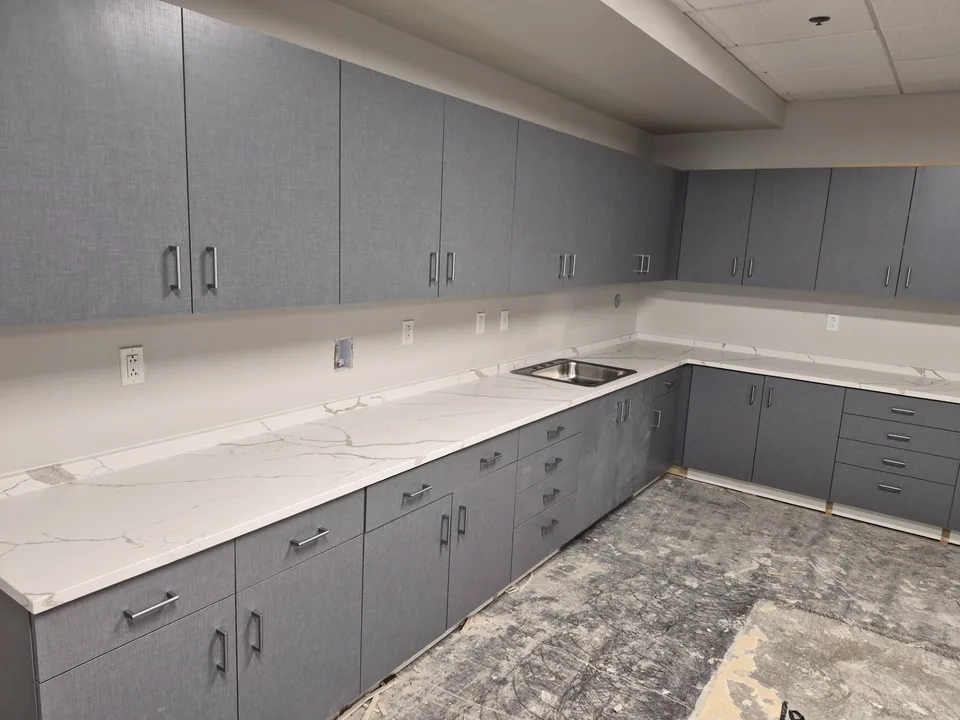 CKC custom upper and lower cabinetry, drawers, sink, and countertop in a commercial workroom.