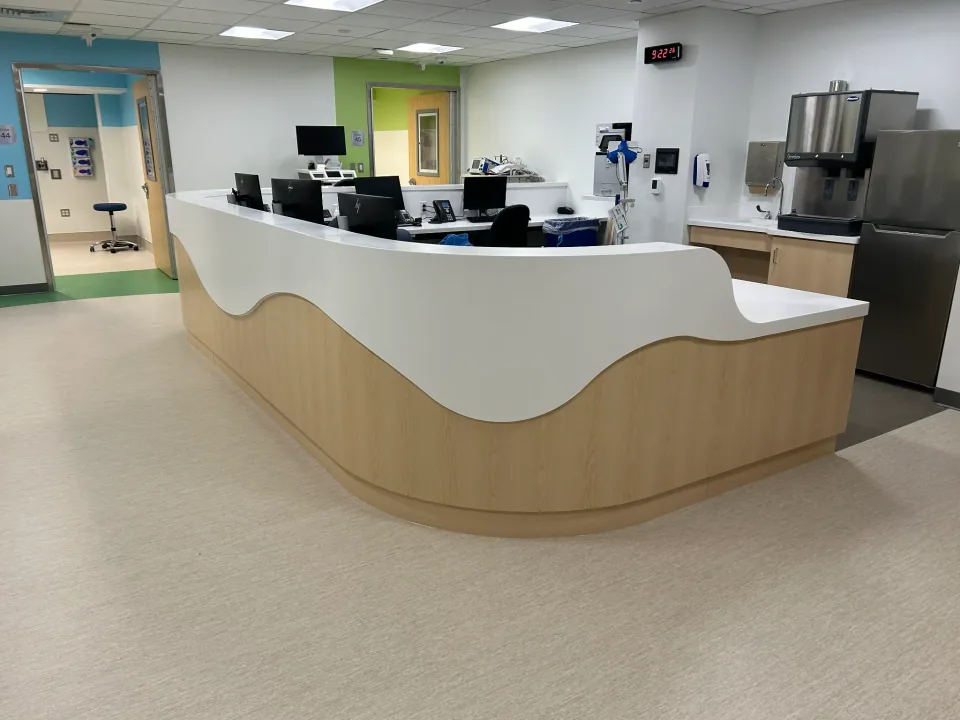 CKC curved white solid-surface reception counter and shaped base in a healthcare interior.