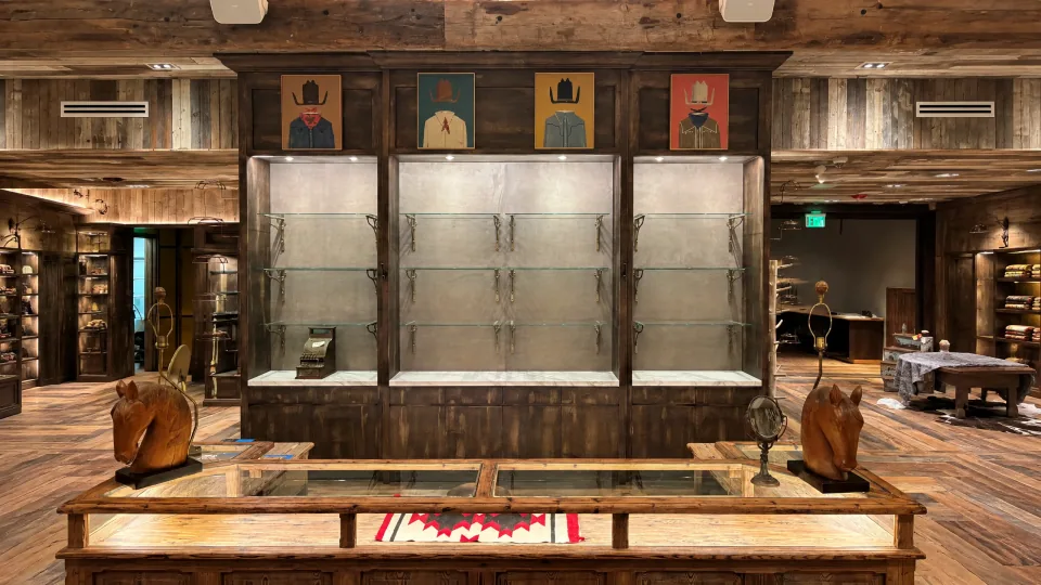 Custom dark-wood retail display fixture with illuminated glass shelving and integrated cabinetry.
